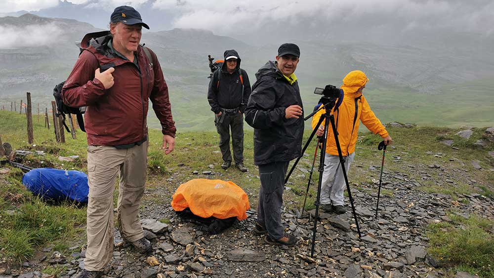 Wandergruppe mit Filmkamera bei Regen auf einem Bergweg